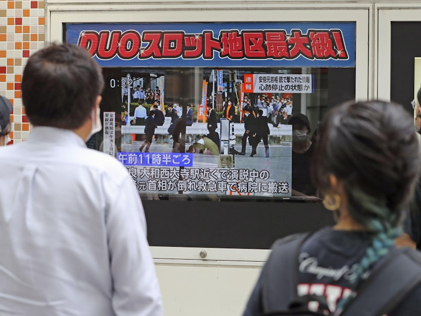 caption: People in Tokyo watch TV news reporting Japan's former Prime Minister Shinzo Abe was shot on Friday.