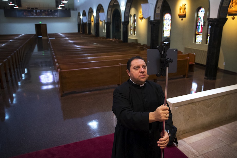 caption: Father Jose Alvarez sets up an iPad ahead of a live-streamed daily mass in Spanish on Friday, April 24, 2020,  at Holy Family Roman Catholic Church in White Center.
