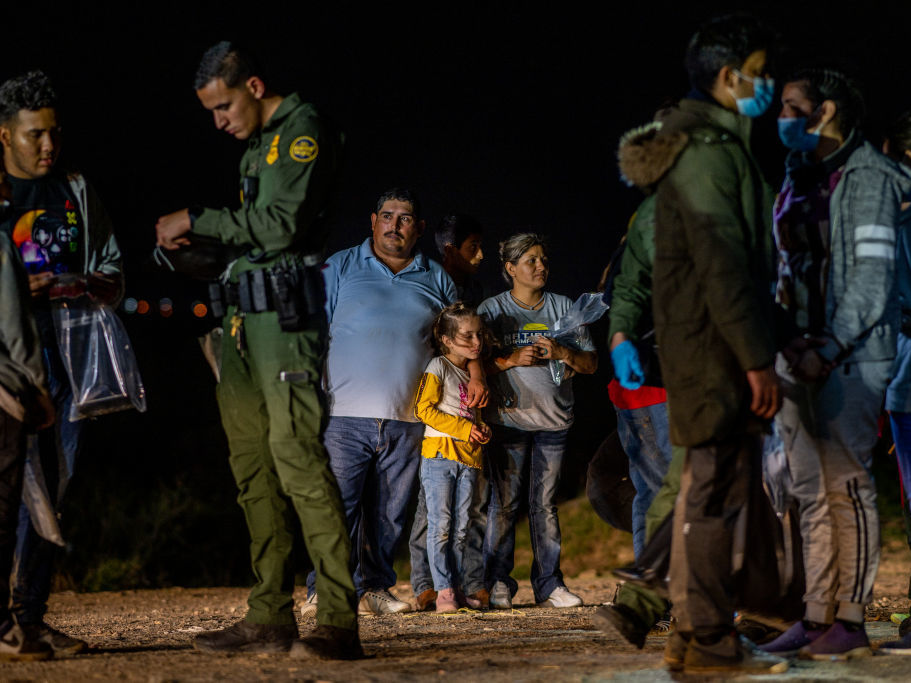 caption: A migrant family stands waiting to be processed on Thursday in Roma, Texas.