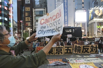 caption: A demonstrator holds a placard during an anti-Olympics demonstration in Tokyo on Monday. A prominent doctors association has joined calls to cancel the Summer Games in Tokyo.