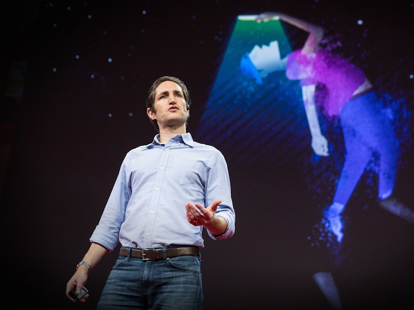 caption: Adam Alter on the TED stage.