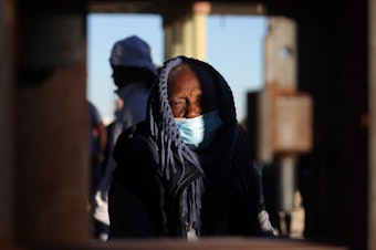 caption: An asylum-seeking migrant from Nicaragua bundles up at the border as she waits to be processed by U.S. Customs and Border Protection after crossing the Rio Grande River into the United States in El Paso, Texas, U.S., December 22, 2022.
