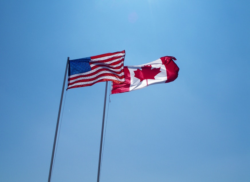 caption: Canada and American flags fly side by side