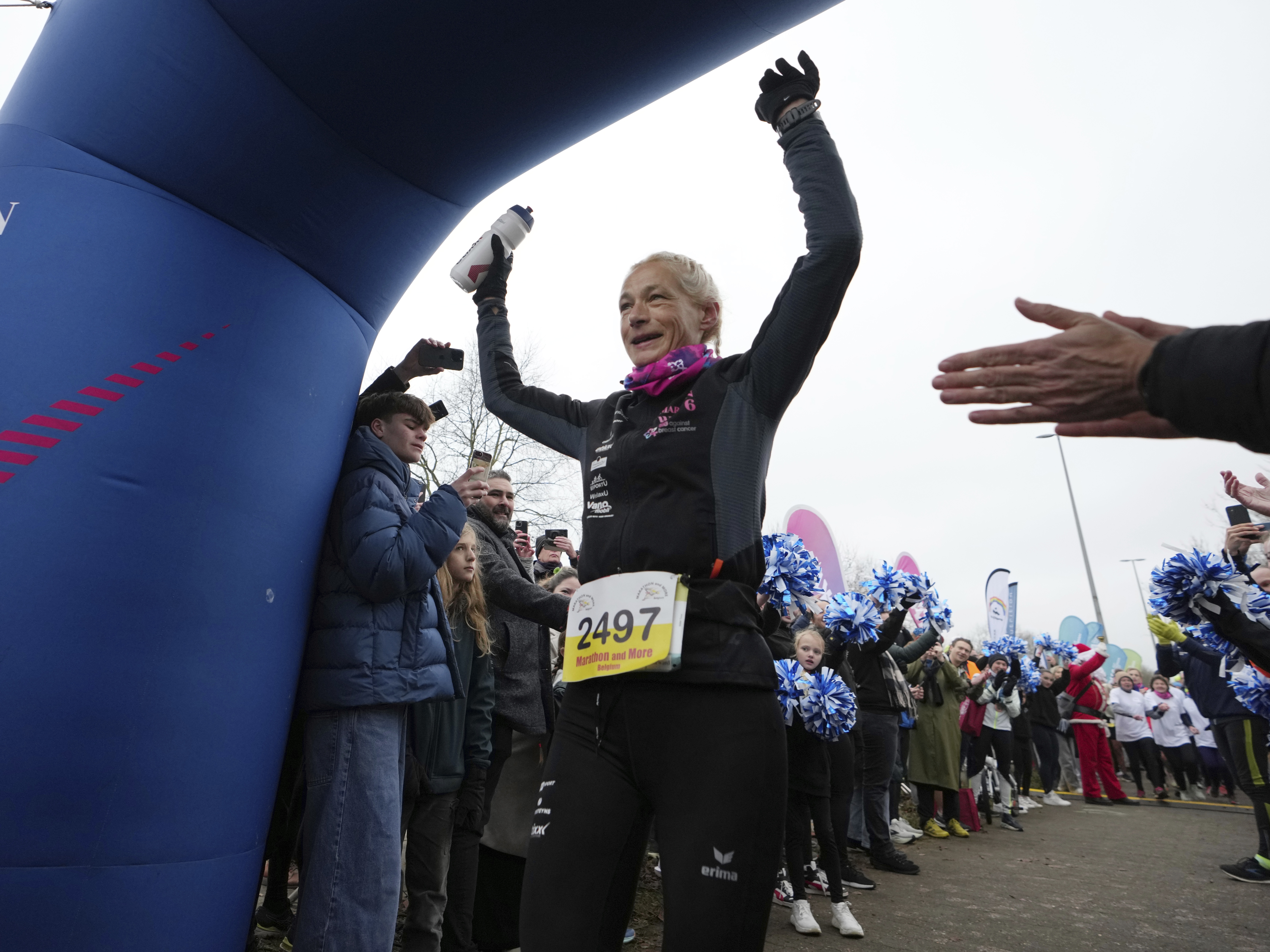 caption: Belgian ultra runner Hilde Dosogne, center, is cheered on as she crosses the finish line during her 366th consecutive marathon in Ghent, Belgium, on Dec. 31, 2024.