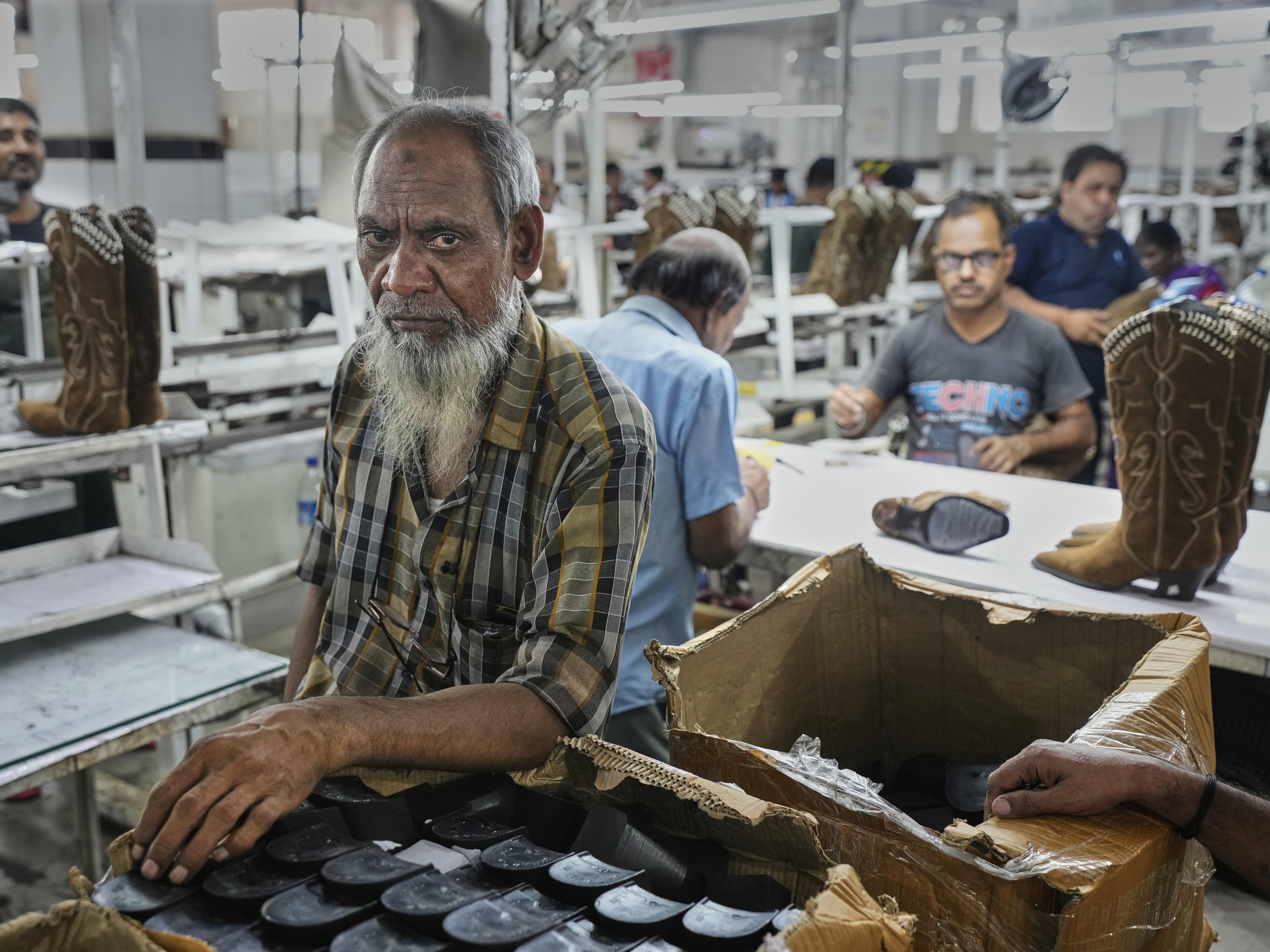 caption: Workers at a manufacturing unit make leather footwear in Agra, India, on Monday.