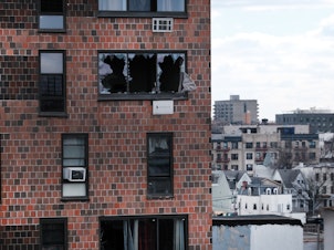 caption: The Bronx apartment building stands a day after a fire swept through the complex where 8 of the 17 people who died were children.
