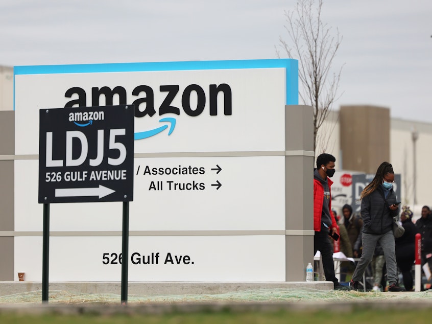caption: Workers walk toward an Amazon warehouse on Staten Island, New York, on April 25, 2022. It's the second Amazon facility on Staten Island to vote on whether to join the Amazon Labor Union.