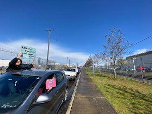 caption: Immigration activists maintain social distancing while protesting outside of the Northwest Detention Center in Tacoma on March 30, 2020. 
