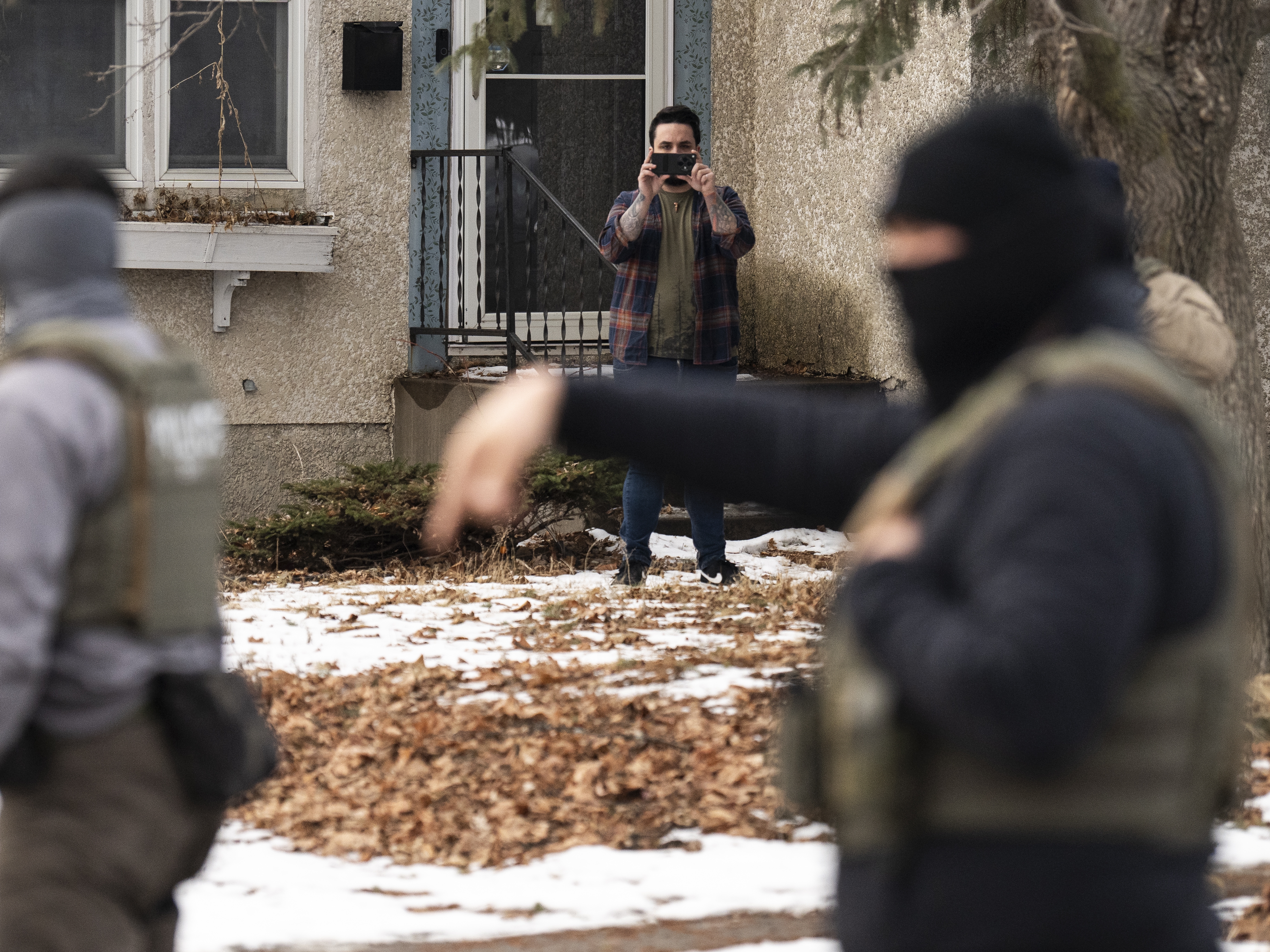 caption: An observer films ICE agents this month in Minneapolis. A new lawsuit alleges federal agents are unconstitutionally retaliating against people who are lawfully observing and recording federal immigration enforcement operations by gathering their personal information and labeling them as domestic terrorists