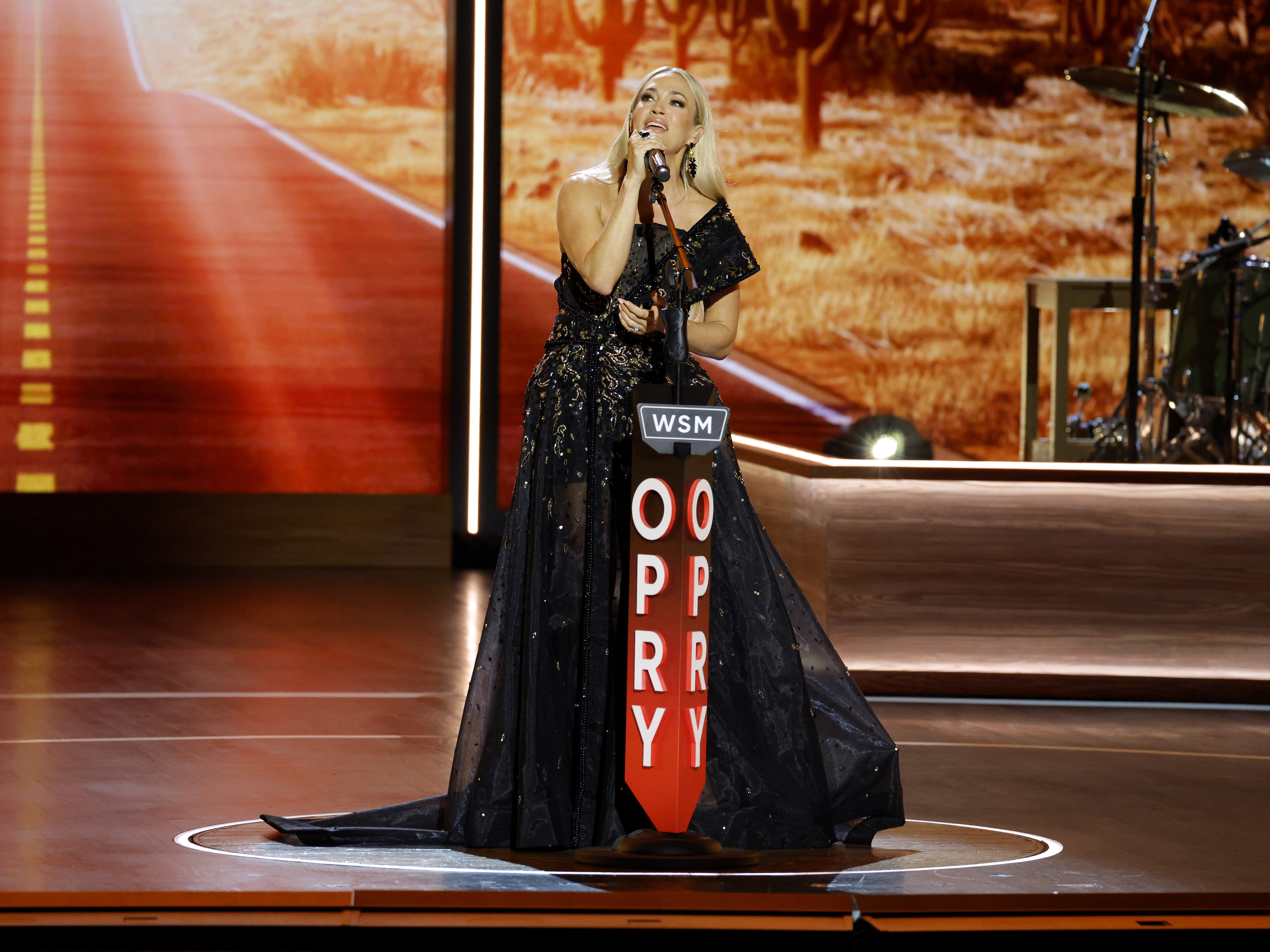 caption: Carrie Underwood performs onstage during a celebration of the Grand Ole Opry's centennial on March 19, 2025 in Nashville, Tenn.