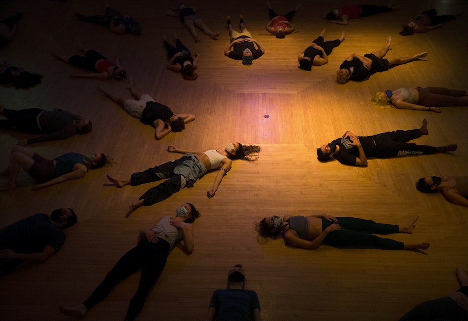 caption: Participants lie on the ground for the duration of one song during a Dance Church class on Tuesday, October 26, 2021, at Washington Hall in Seattle. 