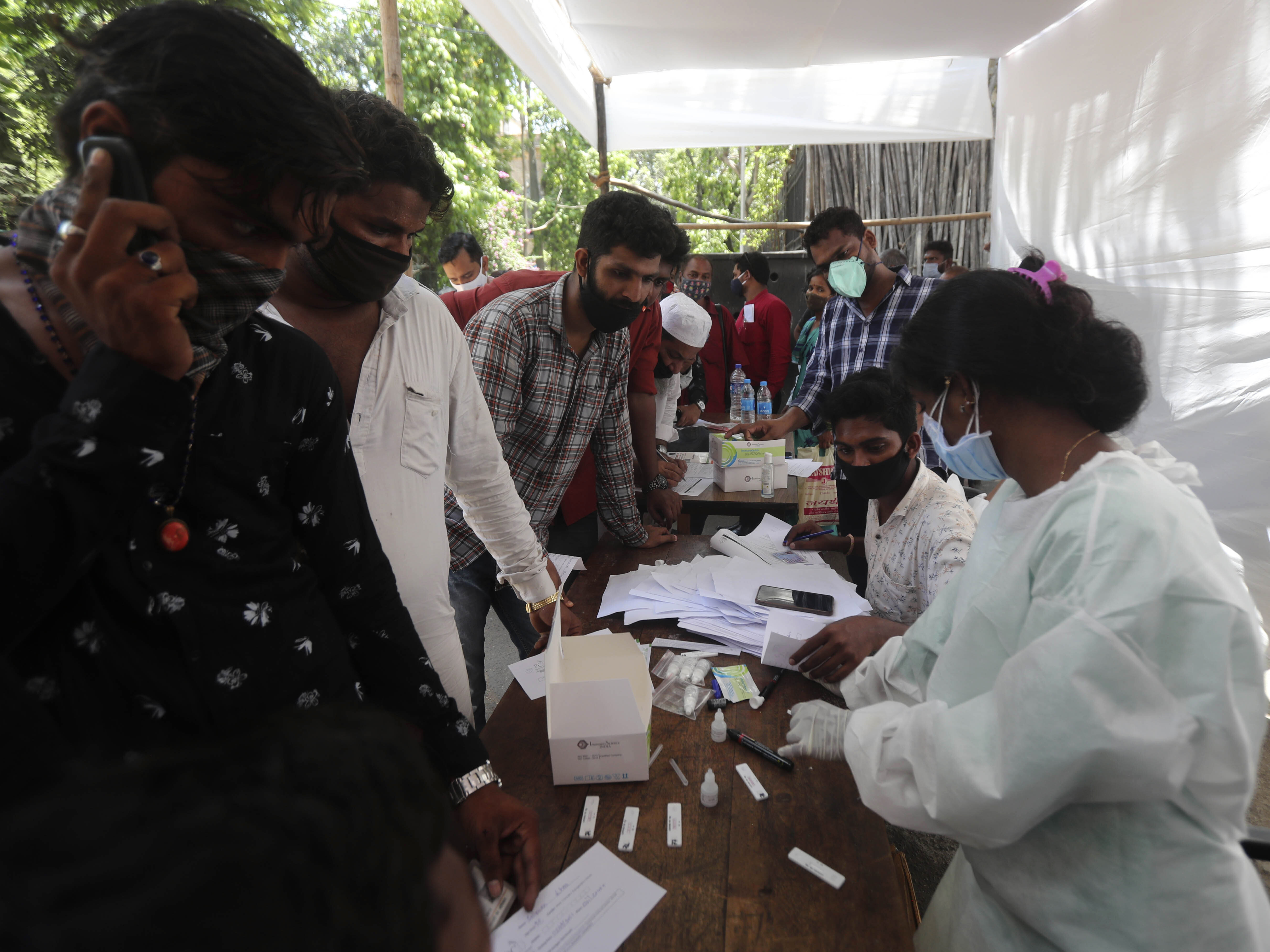 caption: People wait for coronavirus test outside a court in Mumbai on Monday as India reported its biggest single-day spike in confirmed coronavirus cases since the pandemic began.