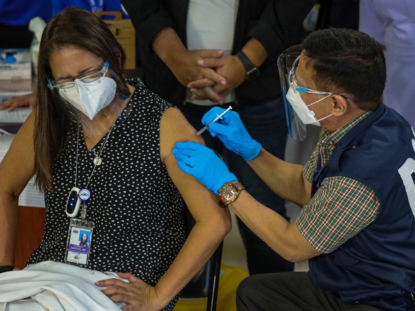 caption: Philippines Health Secretary Francisco Duque III administers the China-made Sinovac COVID-19 vaccine to Eileen Aniceto, a doctor at the Lung Center of the Philippines.