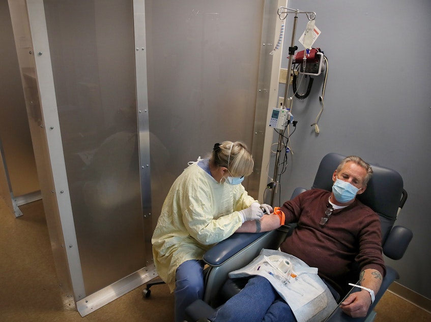 caption: Nurse Janet Gilleran prepares to treat COVID-19 patient Mike Mokler with bamlanivimab, a monoclonal antibody drug from Eli Lilly, at the Respiratory Infection Clinic of Tufts Medical Center in Boston on Dec. 31, 2020.