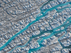 caption: Rivers of meltwater carve into the Greenland ice sheet. Melting at the ice sheet's surface can spur more melt, creating a dangerous feedback loop.