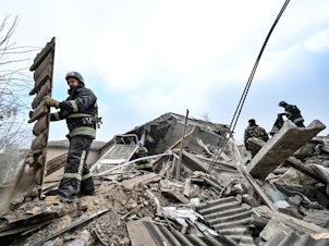 caption: Rescuers remove rubble at the maternity ward of the Vilniansk Multidisciplinary Hospital in Ukraine, one of the countries experiencing an increase in violence against health-care workers.