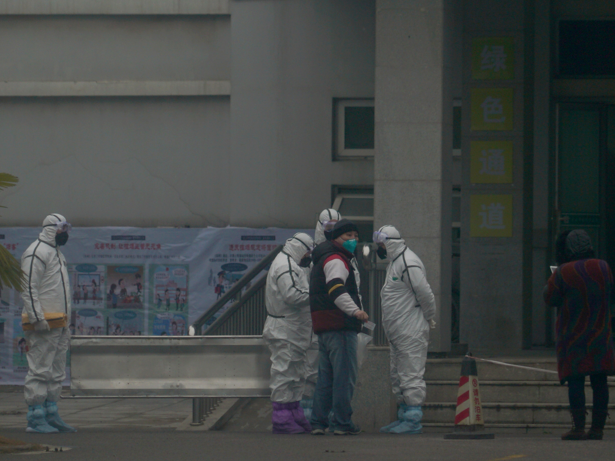 caption: Staff in biohazard suits hold a metal stretcher on Tuesday by the inpatient department of Wuhan Medical Treatment Center in the Chinese city of Wuhan, where some people infected with a novel coronavirus are being treated.