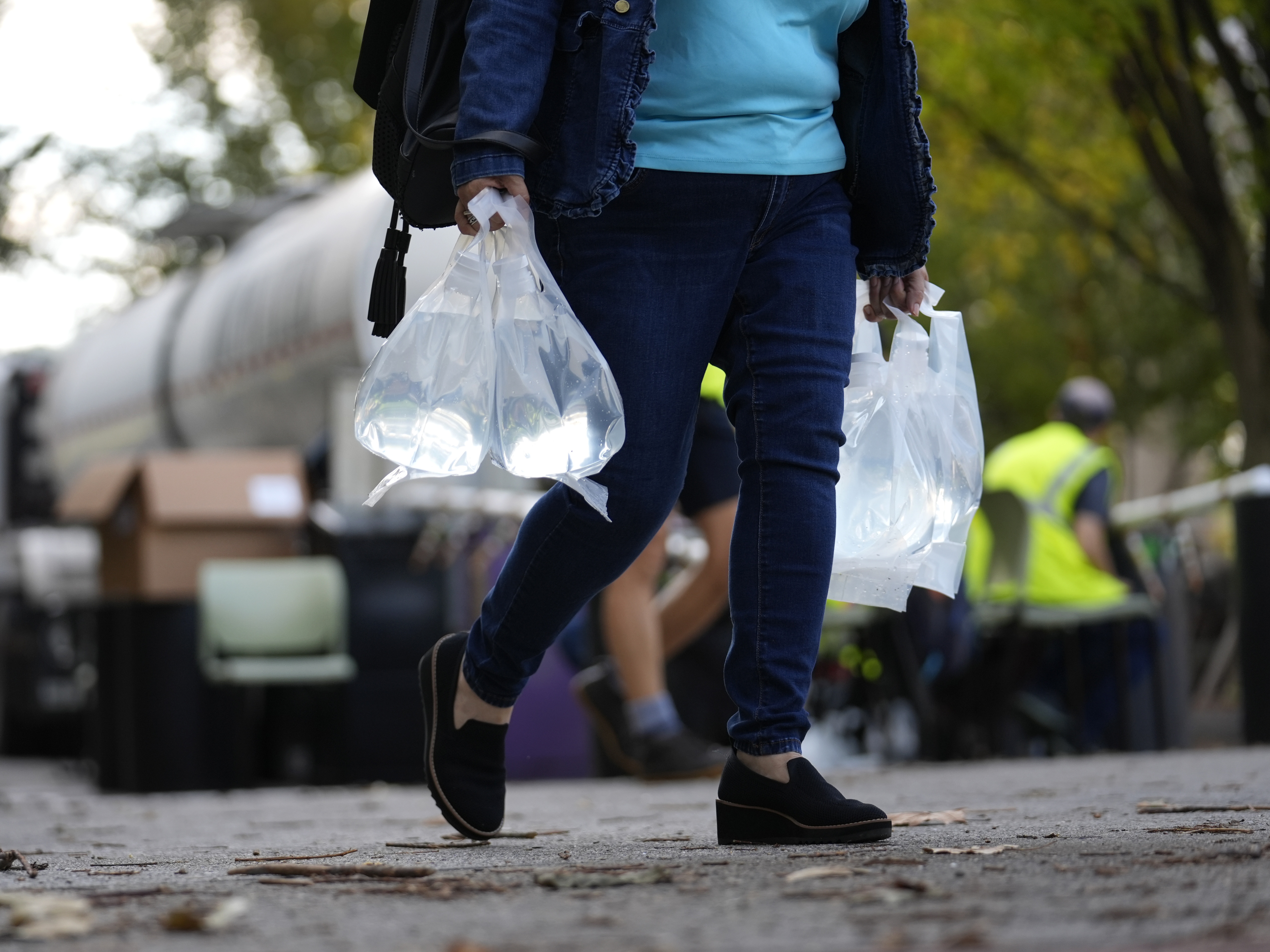 caption: A person carries bags of fresh water after filling up from a tanker at a distribution site in the aftermath of Hurricane Helene on Wednesday in Asheville, N.C.