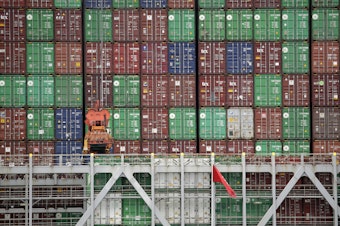 caption: Cargo containers are stacked on a ship at California's Port of Los Angeles.