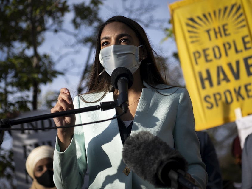 caption: Rep. Alexandria Ocasio-Cortez, D-N.Y., speaks with other Democratic members of Congress outside of the Democratic National Headquarters in November, urging then-President-elect Biden to address the climate crisis.