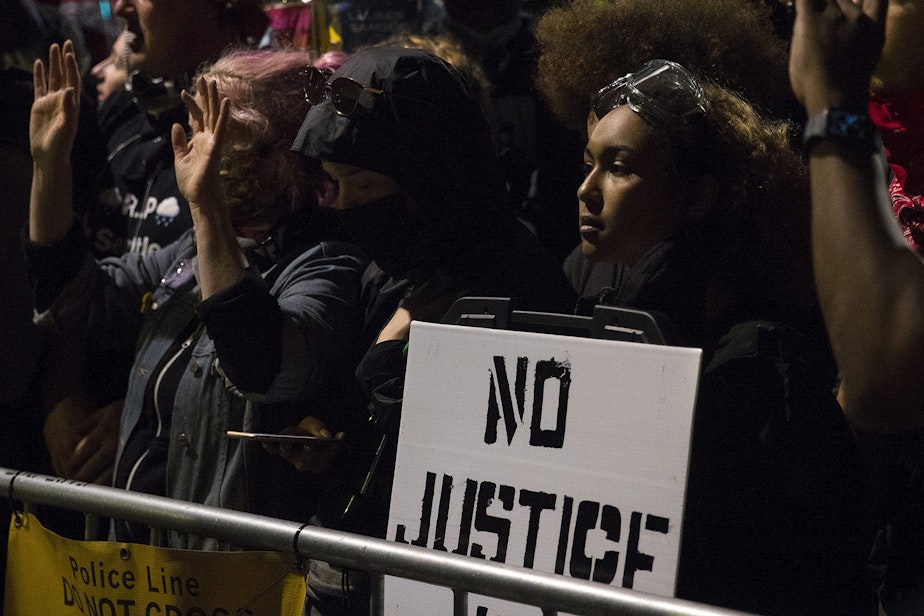 caption: For more than six hours, hundreds of people demonstrating for racial justice and against police brutality stood opposite of a barricade facing Seattle police officers near the department's East Precinct building on Tuesday, June 2, 2020, at the intersection of 11th Avenue and East Pine Street in Seattle. Around 11:30 p.m., officers released tear gas, flash-bang grenades, pepper spray, and rubber bullets on hundreds of people near Cal Anderson Park.