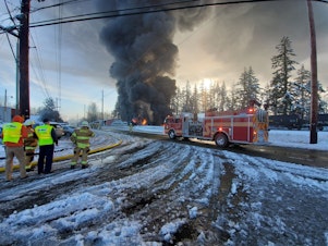 caption: Firefighters watch an oil train burn in Custer, Washington, on Dec. 22, 2020.