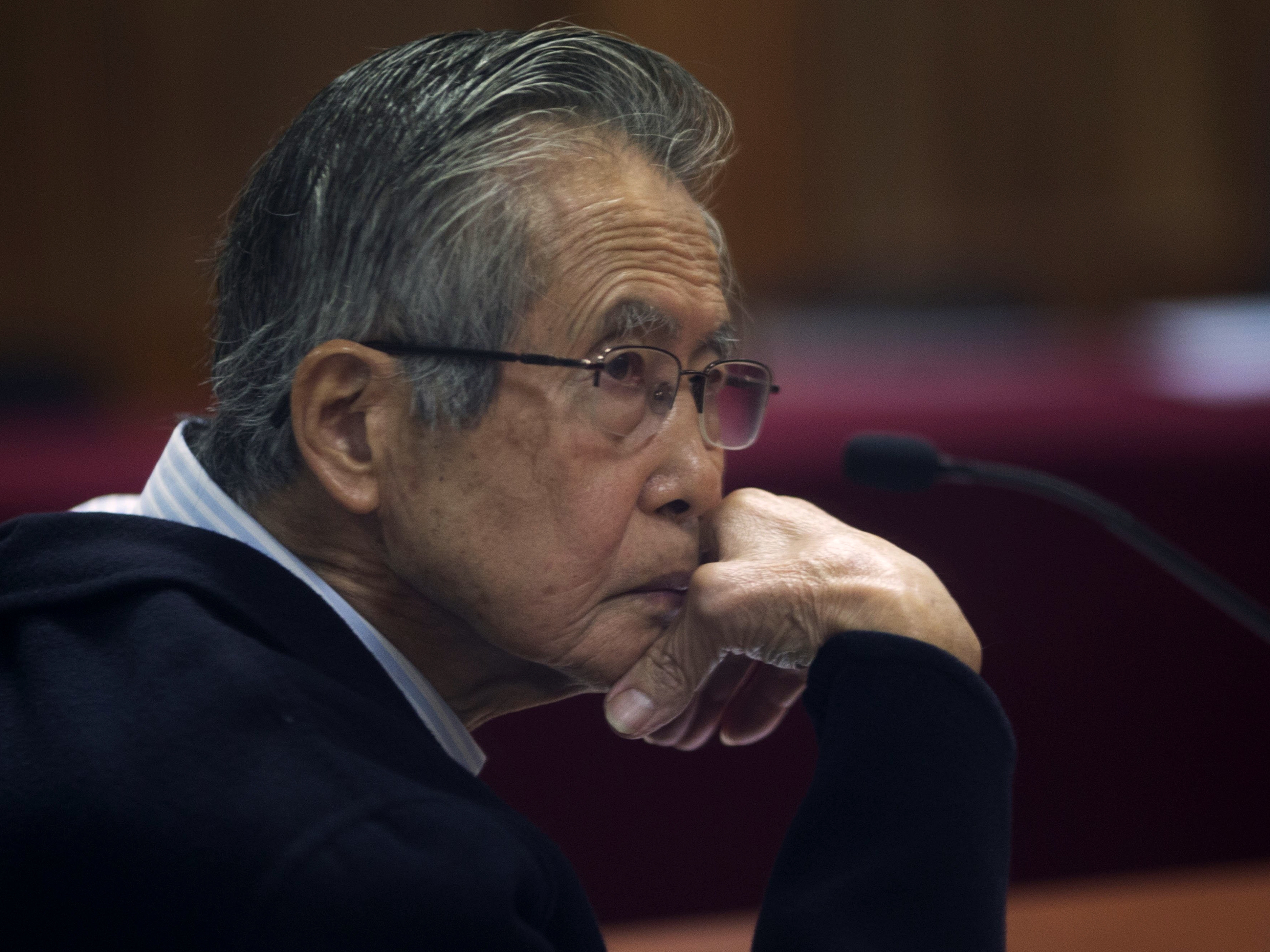 caption: Peru's jailed former President Alberto Fujimori, photographed through a glass window, attends his trial at a police base on the outskirts of Lima, Peru, on June 28, 2016. His daughter Keiko Fujimori announced in a post on X that he died of cancer Wednesday. 