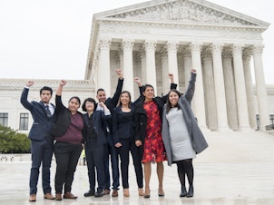 caption: DACA recipients, including Carolina Fung Geng, (3rd from left), plaintiff Martin Batalla Vidal (center) and Eliana Fernández (3rd from right) hold their fists in the air as they enter the U.S. Supreme Court on Tuesday, Nov. 12, 2019.