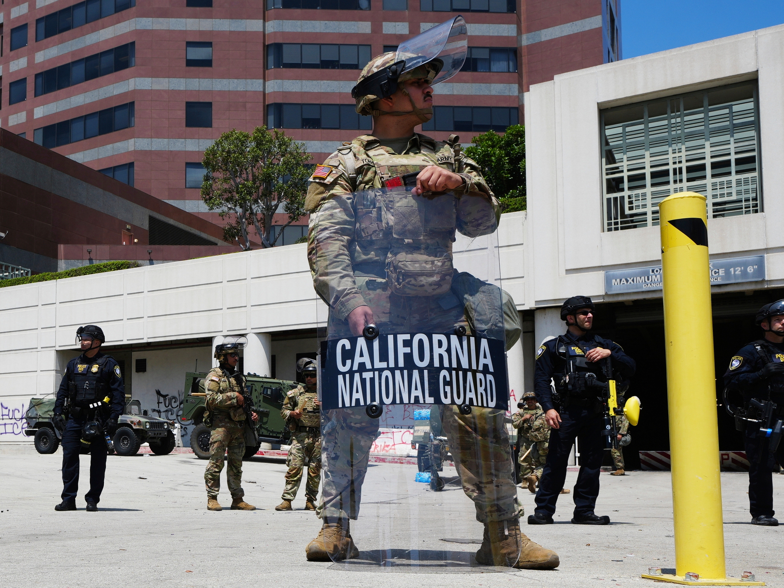 caption: U.S. National Guard stand protect buildings Tuesday, June 10, 2025, in Los Angeles. (AP Photo Damian Dovarganes)