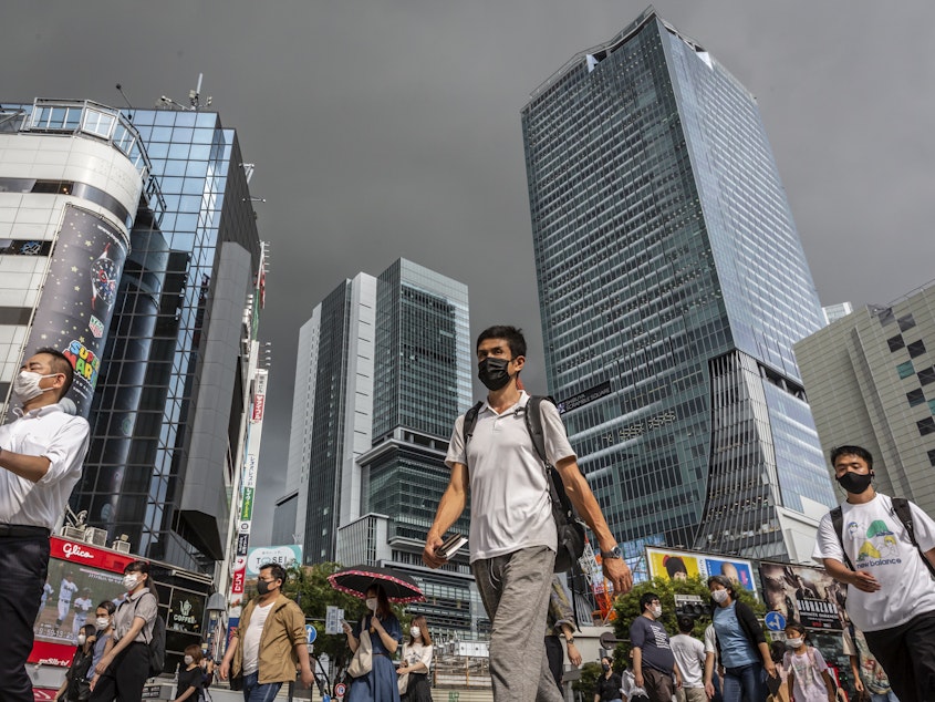 caption: People wearing face masks cross Shibuya crossing on July 30, 2021 in Tokyo, Japan. Tokyo has seen day-on-day record increases in COVID-19 infection rates over the last three days causing concern amongst officials in Tokyo.