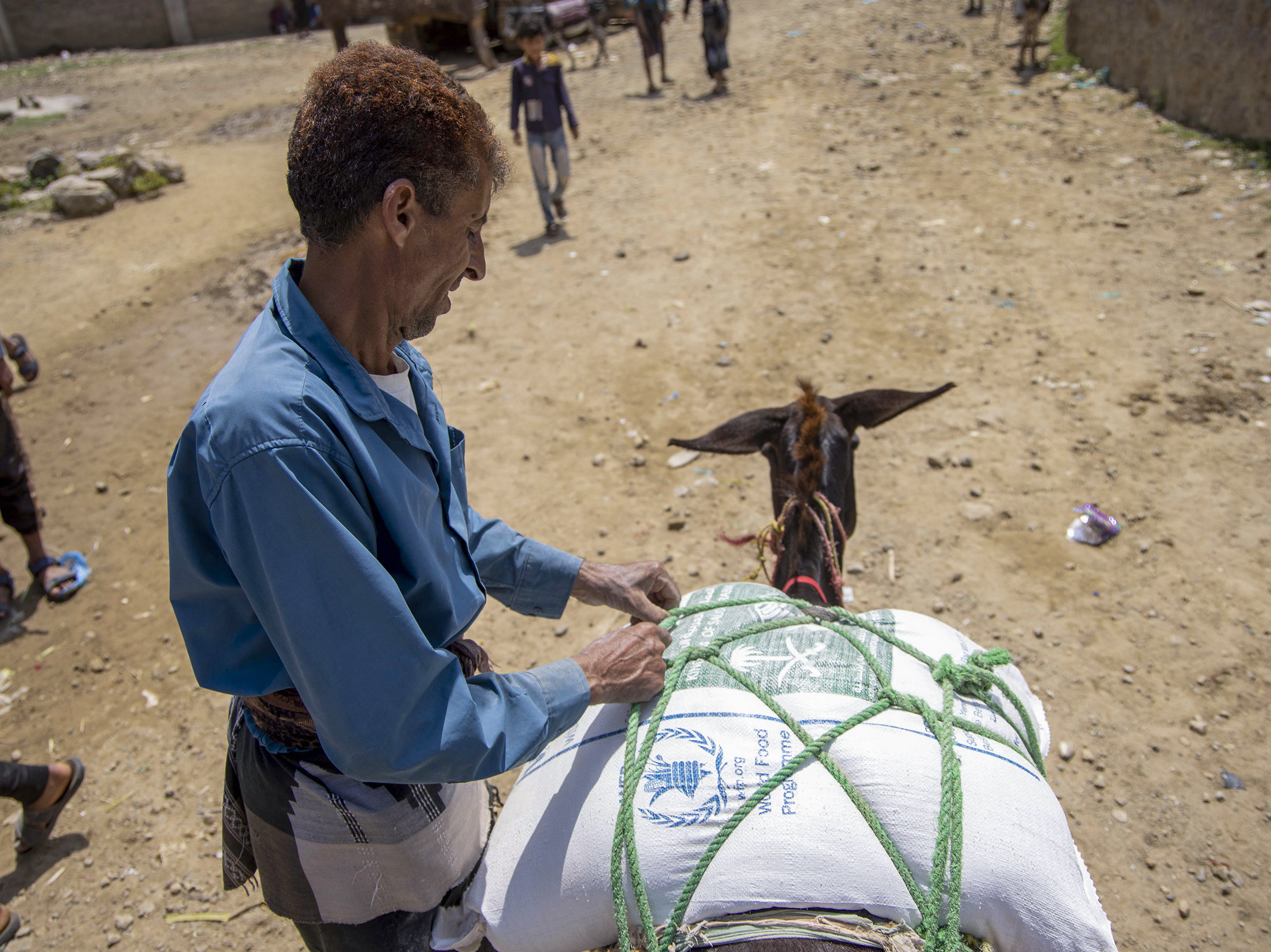 caption: Displaced Yemenis receive humanitarian aid provided by the World Food Programme in the city of Taiz on September 11.