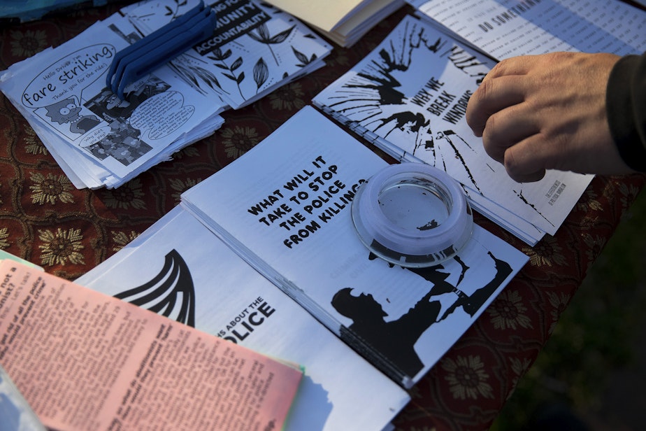 caption: A protester picks up a pamphlet titled, 'Why we break windows,' during a gathering organized by the Seattle Alliance Against Racism and Political Oppression following the reading of the guilty verdict in the trial of Derek Chauvin for the murder of George Floyd, on Tuesday, April 20, 2021, in Seattle.