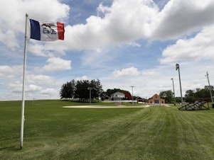 caption: An Iowa flag waves over the field at the Field of Dreams movie site in Dyersville, Iowa, on June 5, 2020.