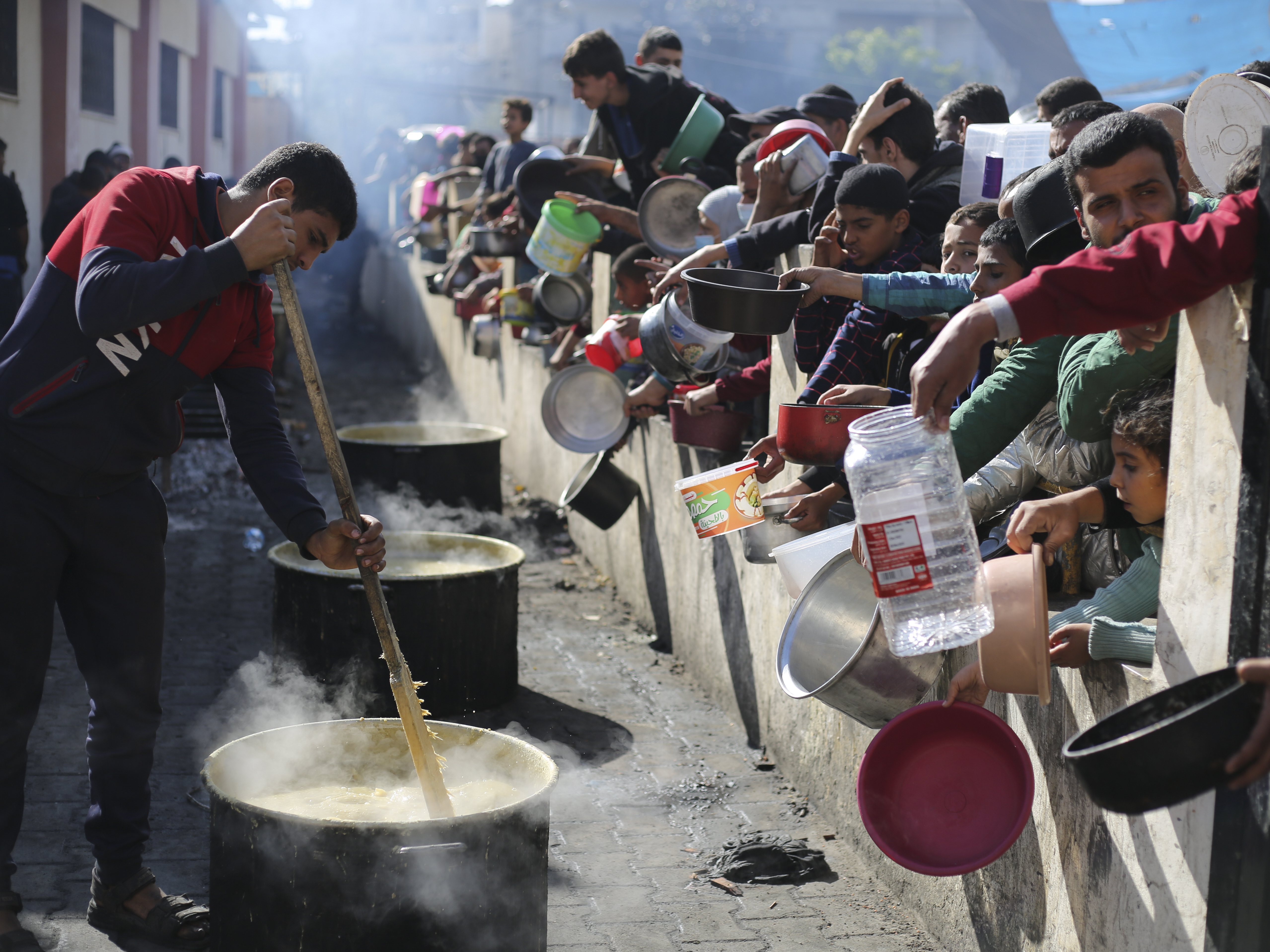 caption: Palestinians line up for a free meal in Rafah, Gaza Strip, on Wednesday, Dec. 20.