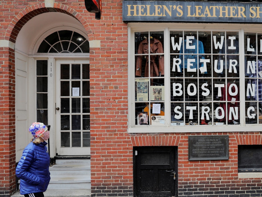caption: A pedestrian walks past a sign in a shop window in Boston on April 28. The coronavirus crisis has shut down much of economy, leaving millions out of work.