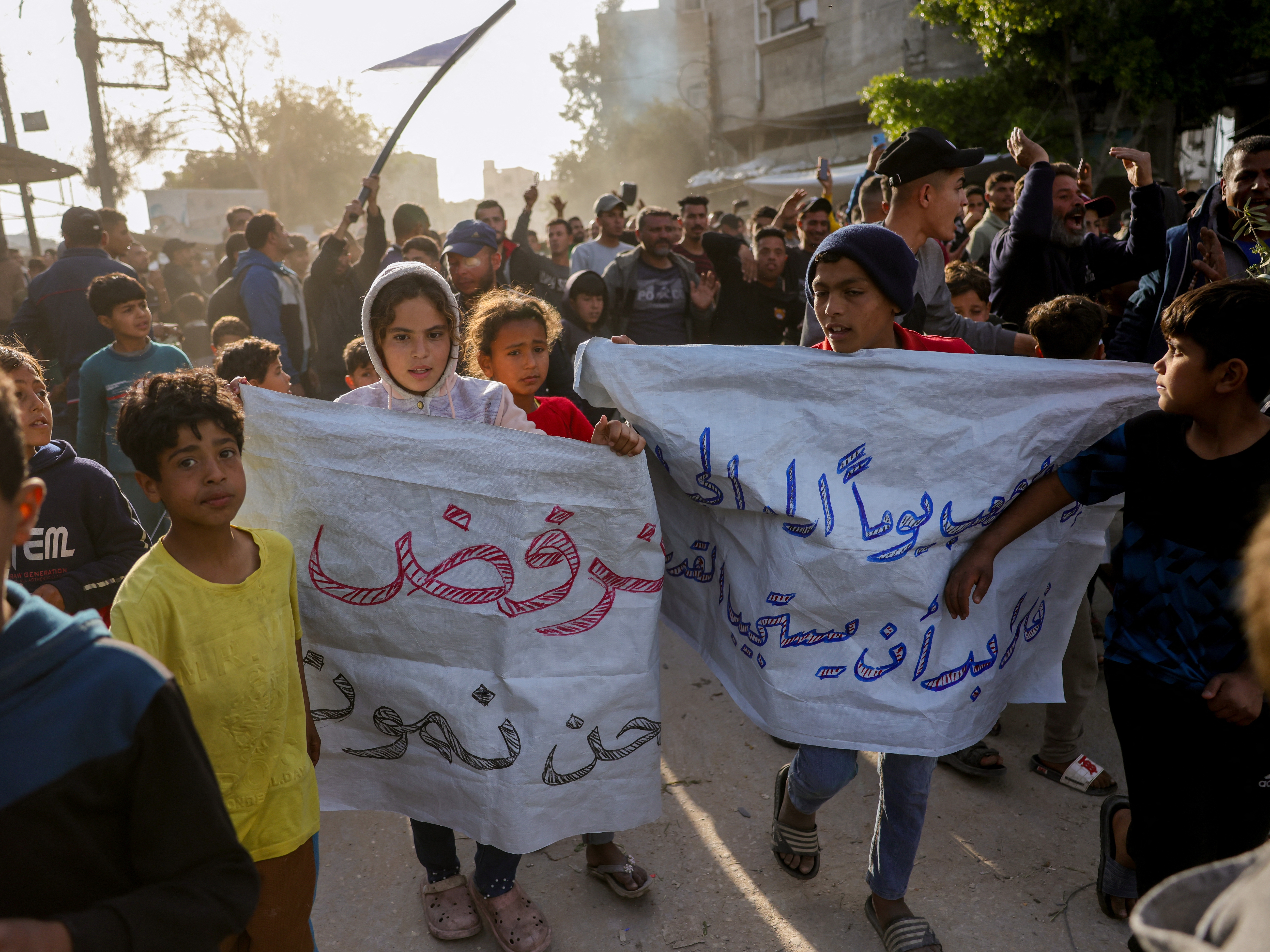 caption: Children carry signs in Arabic that read, "We refuse to die," during a rally calling for an end to the war, in Beit Lahia, in the northern Gaza Strip, on Wednesday.