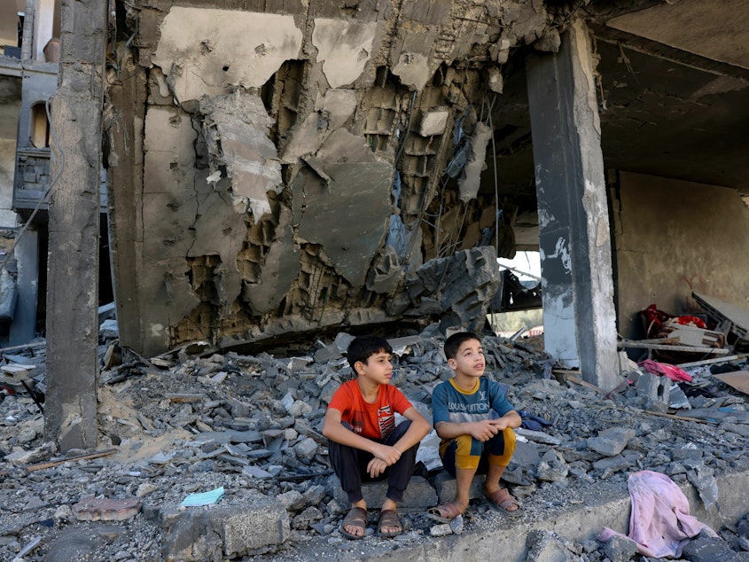 caption: Children sit amid the rubble of a building in the aftermath of an Israeli strike in Rafah in the southern Gaza Strip on Friday.