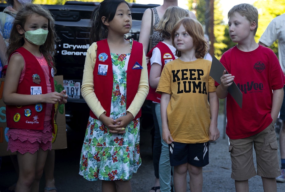caption: Ari Kasprowicz, 8, wears a t-shirt that reads ‘Keep Luma’ while attending a gratitude gathering for the culturally modified elder cedar tree at risk of being cut down to make way for a development project, on Tuesday, July 18, 2023, in the Wedgwood neighborhood of Seattle.