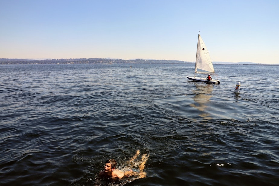 caption: A sailor and a swimmer in Lake Washington near Seattle's Laurelhurst neighborhood on Monday, June 21, 2021, amid record breaking temperatures. The mercury reached 107 at Sea-Tac around the time this photo was taken.
