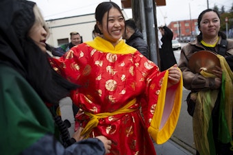 caption: Tiffany Hoang smiles while getting ready to perform with the Mak Fai Lion and Dragon dancers during the Lunar New Year celebration on Saturday, Feb. 4, 2023, in Seattle’s Chinatown-International District. 