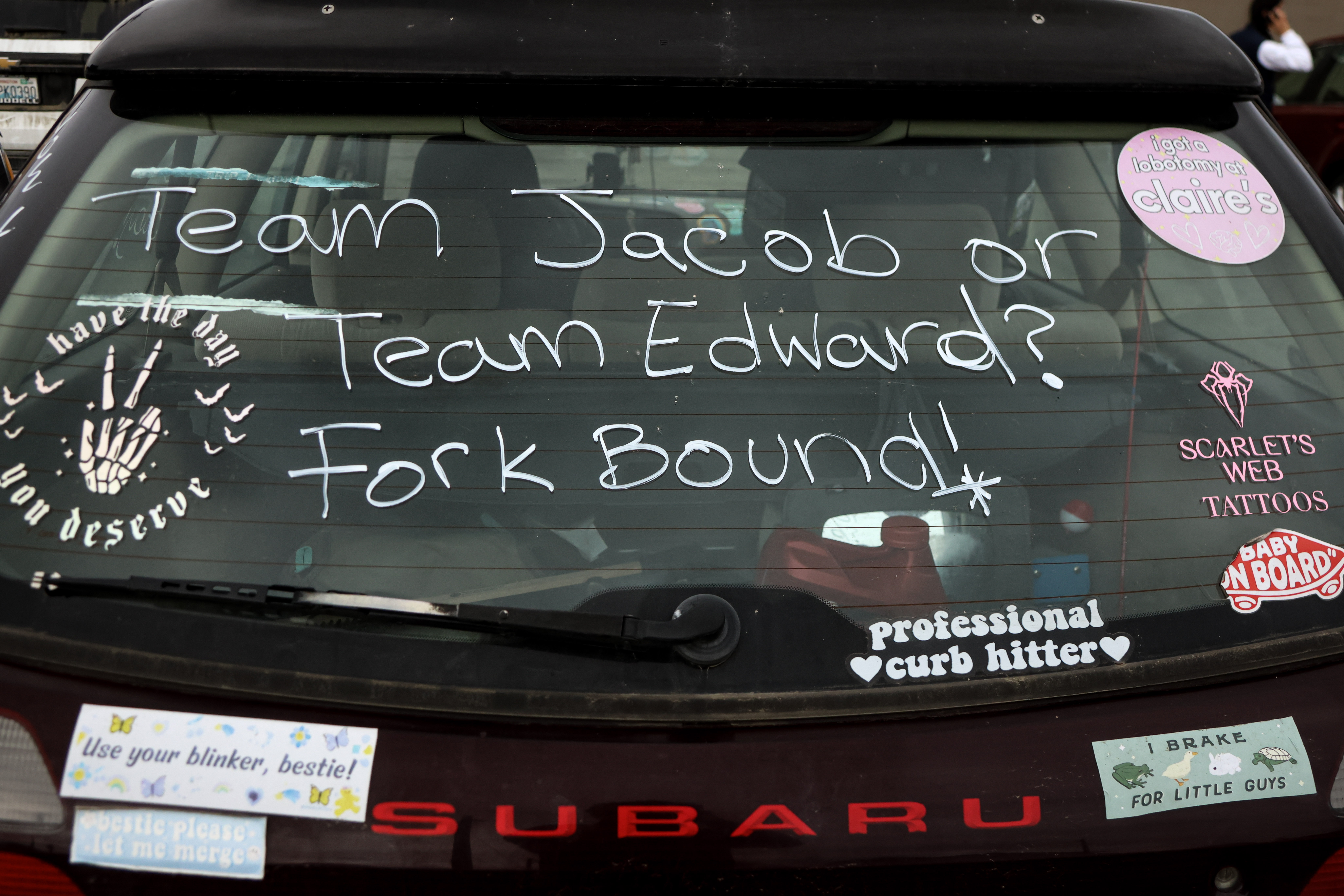 caption: A car sign that reads "Team Jacob or Team Edward" is seen in Forks, Washington. Tourists came to the city to celebrate the 20th anniversary of the "Twilight" movie franchise on September 12, 2025.