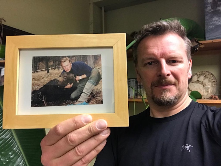 caption: Chris Morgan holds up a picture of himself with Dawson, the grizzly bear he helped catch in the Canadian Rockies while he was in his early twenties.