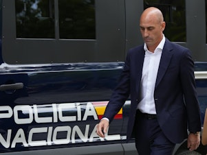 caption: The former president of Spain's soccer federation, Luis Rubiales, passes a police van as he leaves a court appearance in Madrid on Friday.