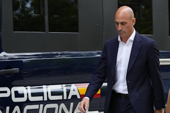 caption: The former president of Spain's soccer federation, Luis Rubiales, passes a police van as he leaves a court appearance in Madrid on Friday.