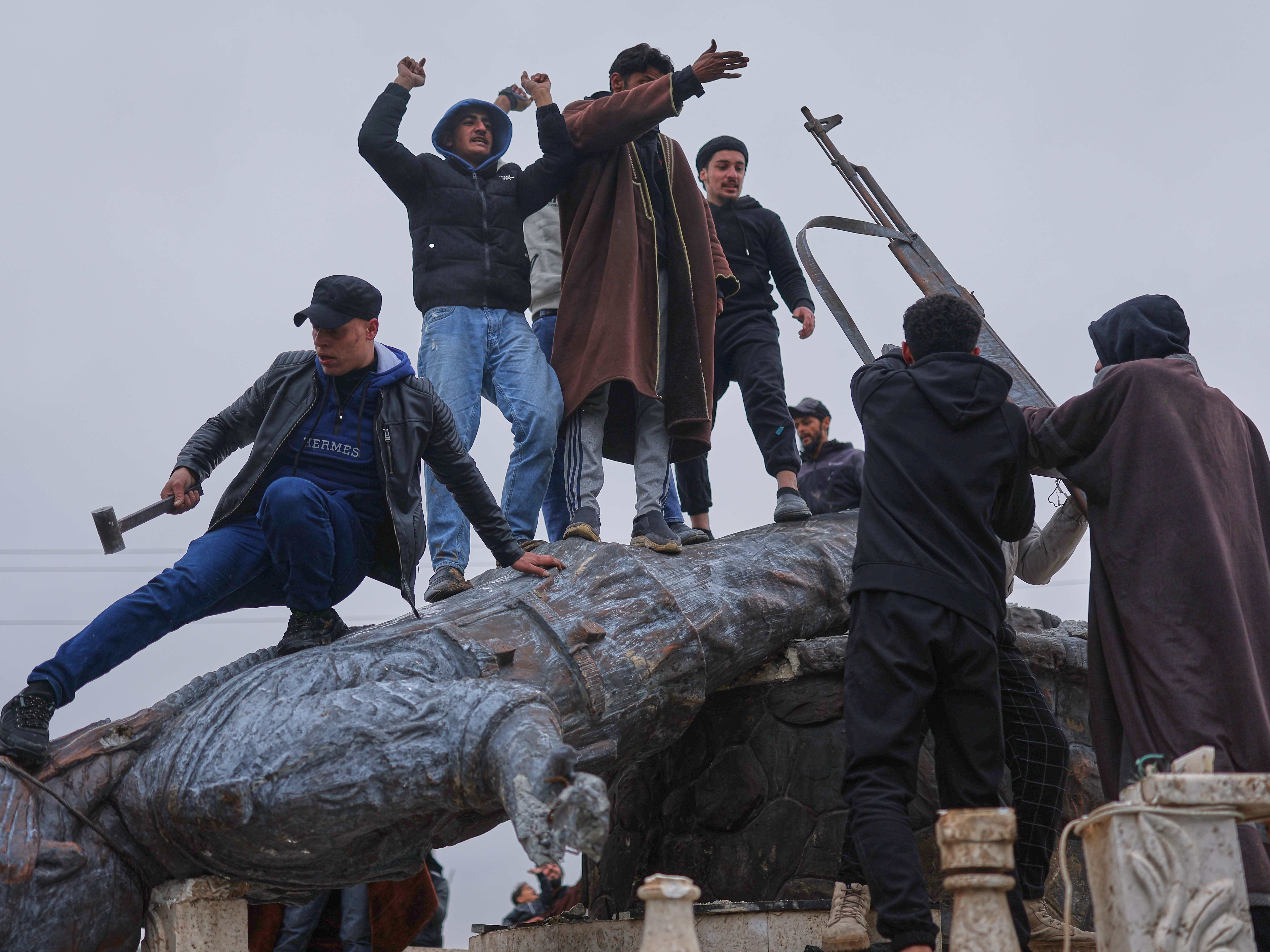 caption: Residents topple a statue of a female Kurdish fighter after the takeover of the town by Syrian government forces from U.S.-backed Syrian Democratic Forces (SDF), in Tabqa, eastern Syria, on Sunday.