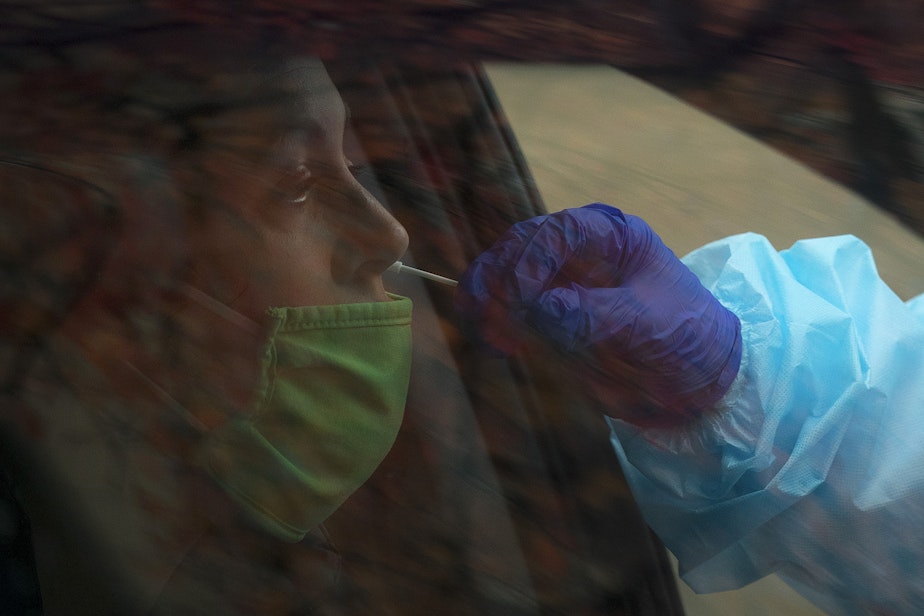 caption: Registered nurse Tina Nguyen administers a Covid-19 test on Friday, November 20, 2020, at the International Community Health Services drive thru testing site on 8th Avenue South in Seattle's International District.