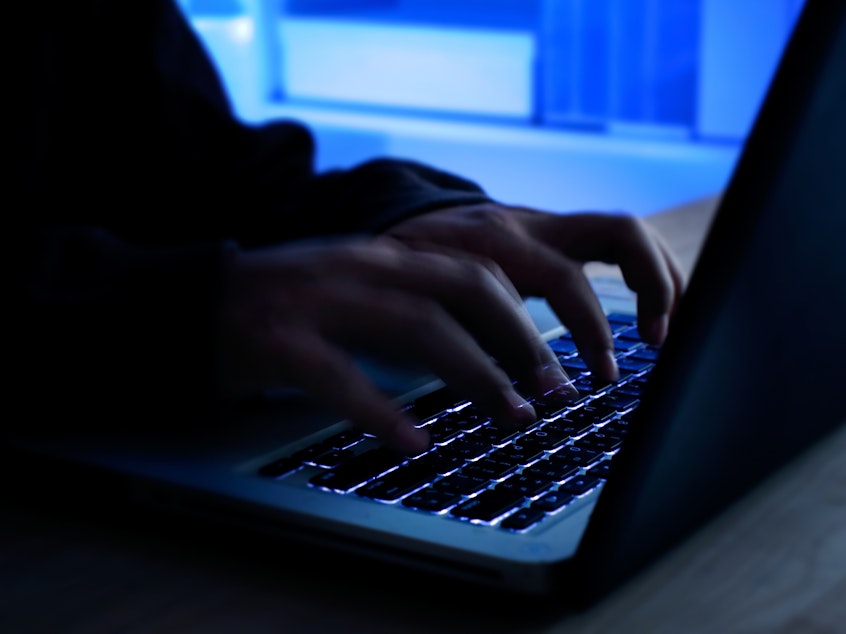 caption: A computer programmer prints a code on a laptop keyboard.