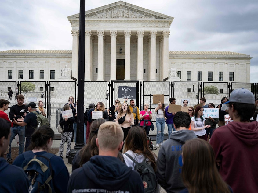 caption: A line of anti-abortion demonstrators watch as abortion rights demonstrators chant in front of an unscalable fence that stands around the U.S. Supreme Court in Washington, D.C., on Thursday.