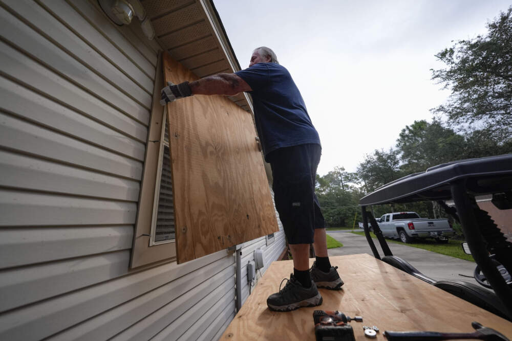 caption: Dave McCurley boards up the windows to his home in advance of Hurricane Helene, expected to make landfall Wednesday. (Gerald Herbert/AP)