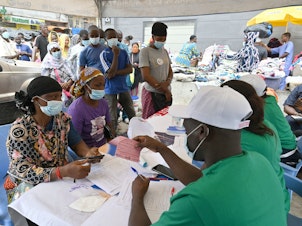 caption: People line up to receive a Pfizer COVID-19 vaccine dose during a mass vaccination campaign in Abidjan, Ivory Coast, in August 2021.
